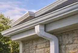 White aluminum gutter along a shingle roof edge