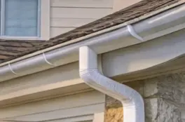 Half-round white gutter below a shingle roof