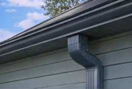 Dark steel gutter and downspout on a home with gray siding