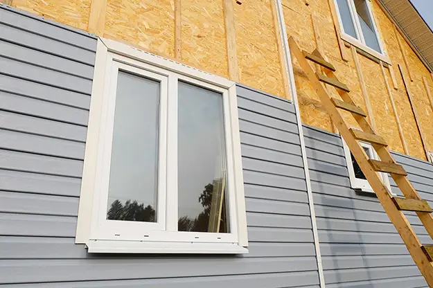 Gray vinyl siding installed around a white window