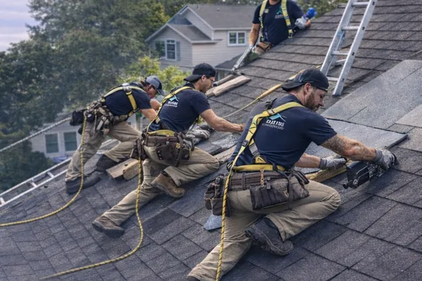 Roofers replacing missing shingles on an asphalt roof